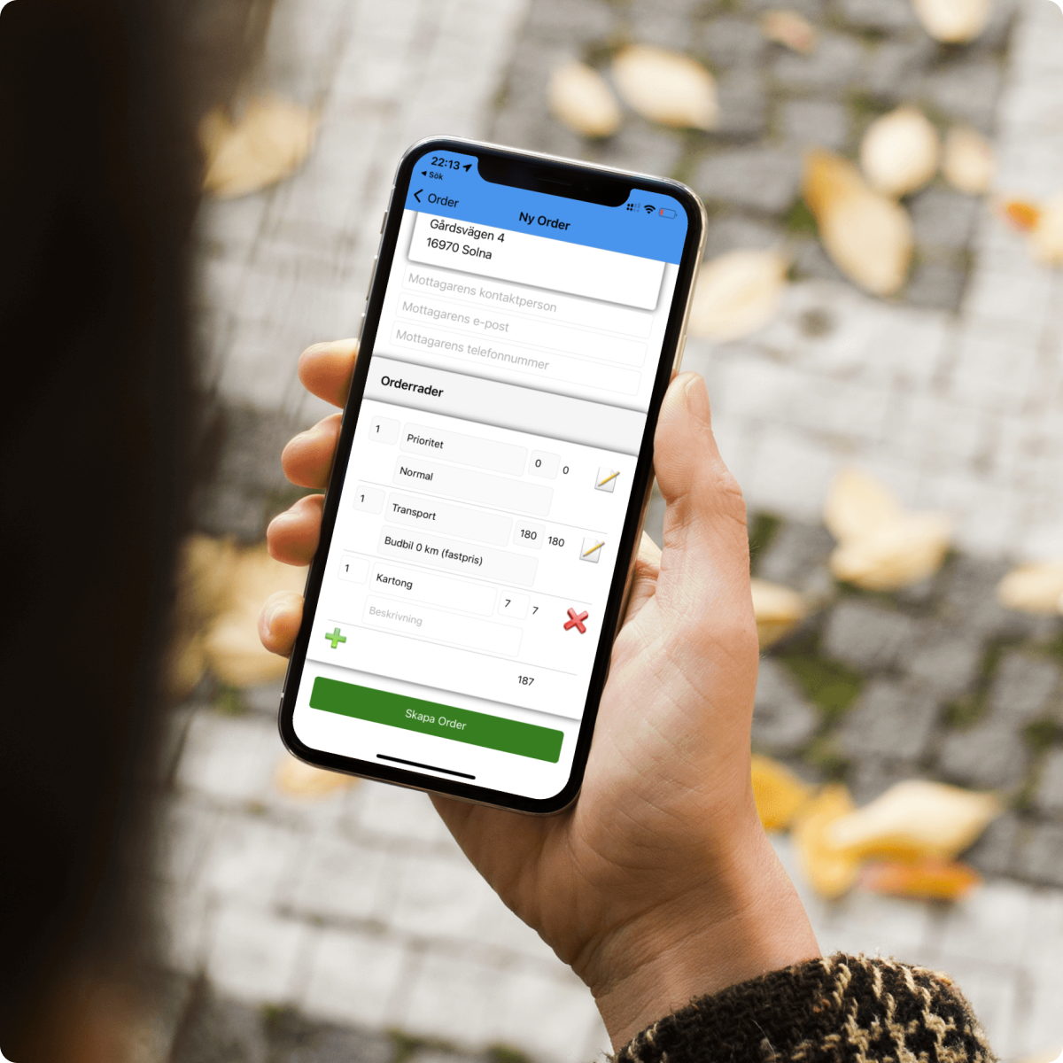 Hand som håller en mobil med förarappen Fleetia Drive öppen